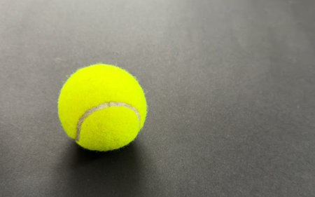 Yellow tennis ball on a black background.