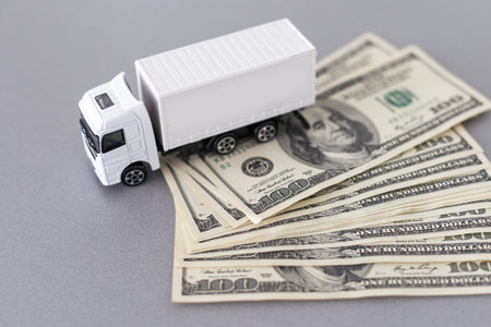 White toy truck lie on dollars, space for text.