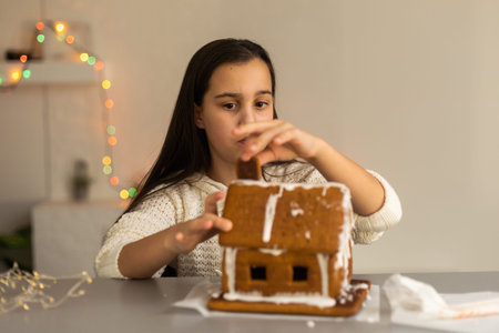 Cute little girl with gingerbread spooky house with festive icing and ghost shaped cookie. Happy Halloweenの写真素材