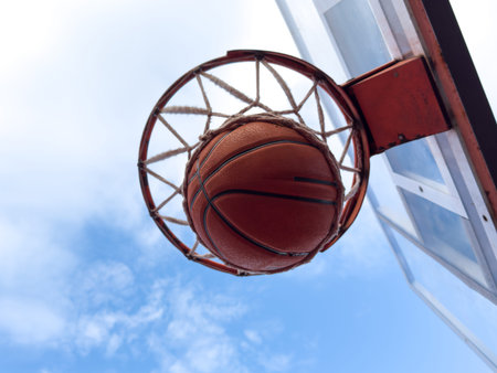 Basketball ball and basketball hoop outdoors on sky background.