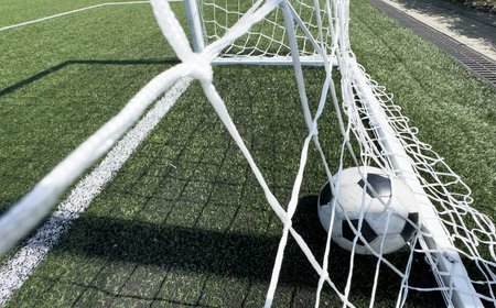 Soccer ball on artificial bright and dark green grass at public outdoor football stadium