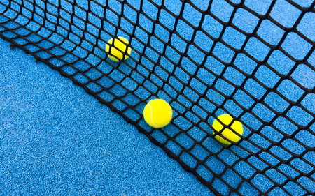paddle tennis balls near the lines of a blue paddle tennis court, racket sports conceptの写真素材