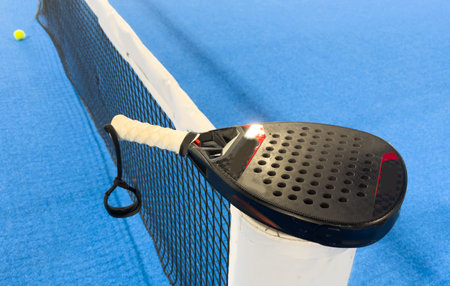 padel racket on a padel blue court with a ballの写真素材