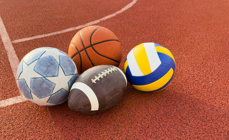 A variety of sports equipment including an american football, a soccer ball, and a basketballの写真素材
