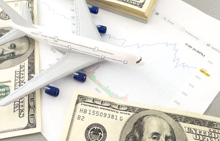 american banknotes and figure of a white plane on a downward trending graphの写真素材