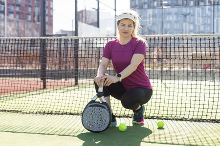 Young sporty woman playing padel game in court on sunny dayの写真素材