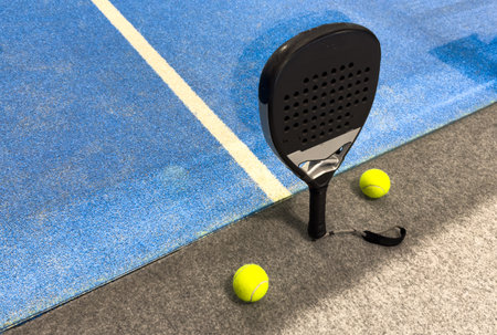 padel racket on a padel blue court with a ballの写真素材