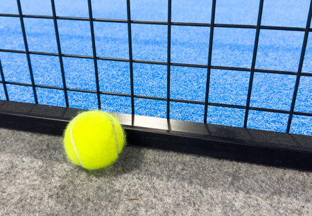 paddle tennis ball over the line on a blue artificial turf court