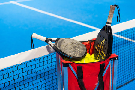 Paddle tennis: Padel racket and ball in front of an outdoor court.の写真素材