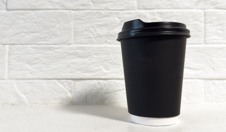 Closeup front view disposable black paper coffee cup with head isolated on white backgroundの写真素材