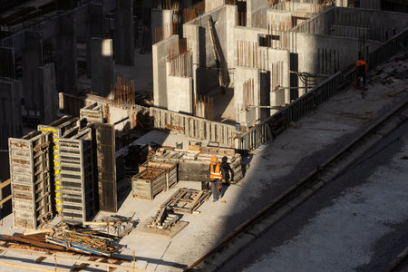Aerial view of busy industrial under construction site workers working with cranes and excavators....