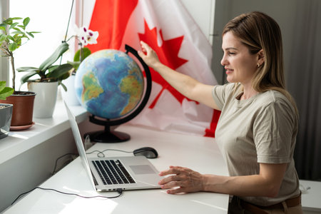 Young female student with Canadian flag and laptop with space for textの写真素材