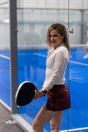 Player on a blue padel court indoor holding a racket and wearing athletic attireの写真素材