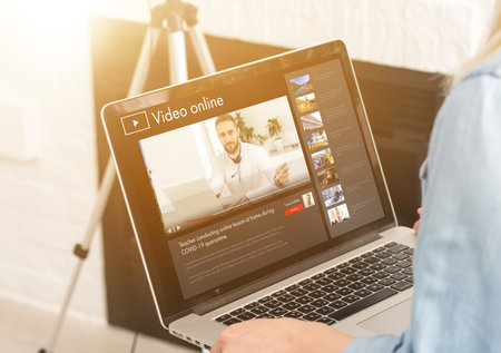 School teen girl student wears headphones distance learning with online teacher on computer screen. Web tutor gives remote class teaching teenage pupil elearning from home. Over shoulder close up viewの写真素材