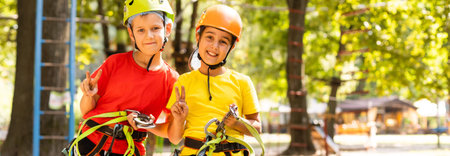 Small children climb a rope bridge in a rope park. Children are having fun in the adventure park. A...