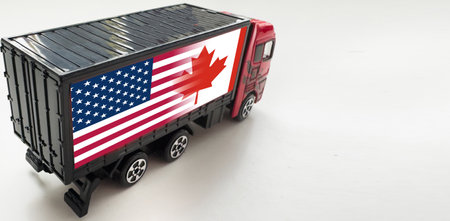 A truck with the national flag of Canada depicted on the back door carries goods to another country along the highway. Concept of export-import, transportation, national delivery of goodsの写真素材