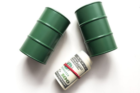 Pump jack and a black barrel on US USD dollar notes, depicts the money received or earned from sales after investment in the development of oil industry.の写真素材
