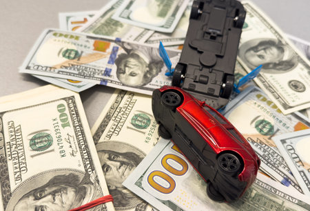 Toy cars in accident on a background of 100 dollar billsの写真素材