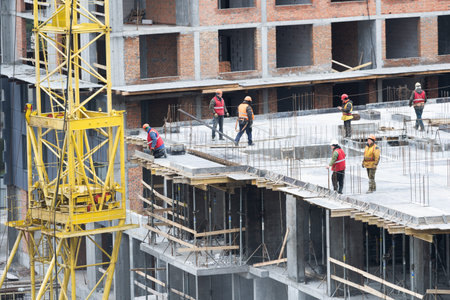 concreting work: construction site worker during concrete pouring into formwork at building area...