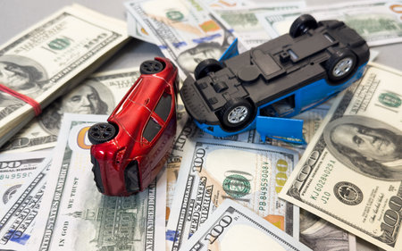 Toy cars in accident on a background of 100 dollar billsの写真素材