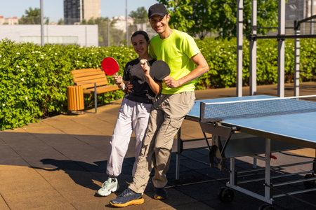 Happy man with his daughter playing ping pong in parkの写真素材