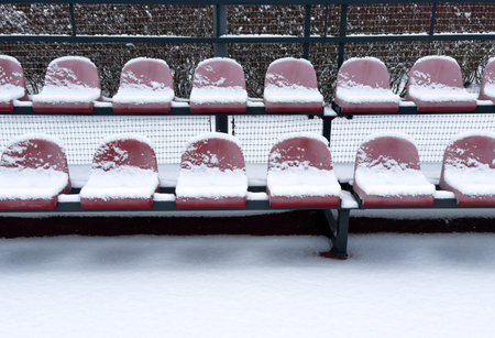 Empty outdoor sports stadium plastic seats on steel supports covered with snow in winter