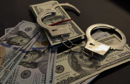 Handcuffs on 100 Bills on Concrete Floor for Crimeの写真素材