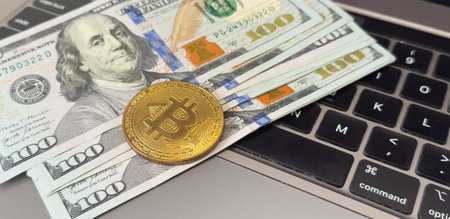 Golden bitcoin with dollar bills on computer keyboard