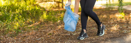 young woman volunteers picking up trash in park. Concept of environmental protectionの写真素材
