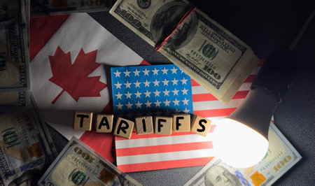 Tariffs between the United States and Canada. USA and Canadian flags, and wooden cubes with word tariffs.の写真素材
