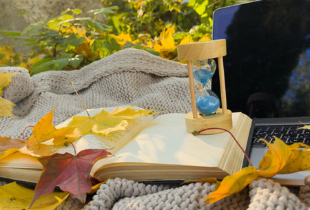 hourglass and laptop in autumn leaf