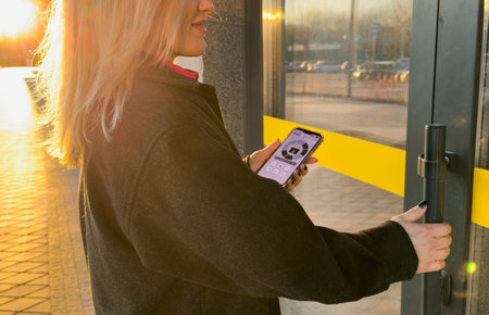 Woman locking smartlock on the entrance door using a smart phone. Concept of using smart electronic locks with keyless access.の写真素材