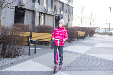 little girl riding a scooter in the Park on a Sunny spring day. Active leisure and outdoor sport for childrenの写真素材
