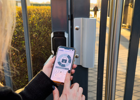 Woman locking smartlock on the entrance door using a smart phone. Concept of using smart electronic locks with keyless access.の写真素材