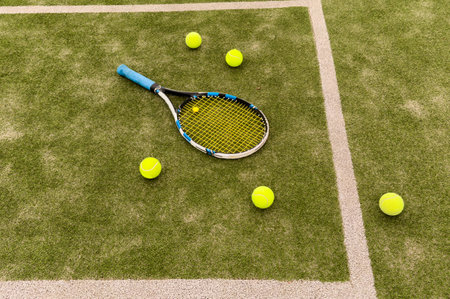 A tennis racket and new tennis ball on a tennis courtの写真素材