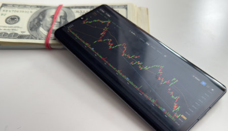 Stock exchange on smartphones screen and dollars banknotes blurredの写真素材