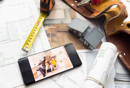 Architectural model on desk with smartphone, drawing technical tools and blueprints. Architecture, building, construction and real estate business.の写真素材