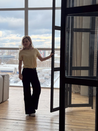 Blond woman in black outfit posing on terrace. Portrait of happy girl smiling and resting on balcony.の写真素材