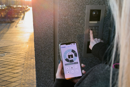 Woman locking smartlock on the entrance door using a smart phone. Concept of using smart electronic...