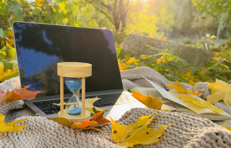 hourglass and laptop in autumn leafの写真素材