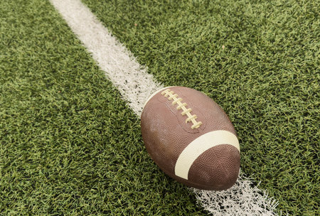 American football ball on green grass field background.の写真素材