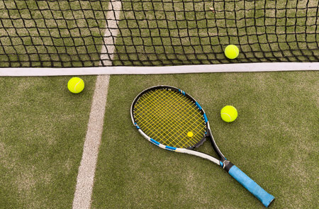 A tennis racket and new tennis ball on a tennis courtの写真素材
