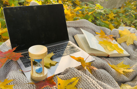 hourglass and laptop in autumn leaf