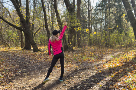 Autumn forest run path. Fall trail runner woman running in beautiful foliage woods nature background. Asian happy sports woman training outdoor.の写真素材