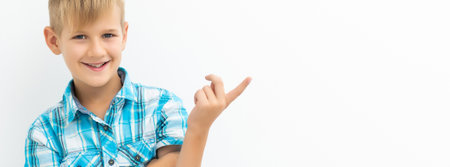 Caucasian boy in a blue plaid shirt is thinking about something on a white background. Portrait of a child with one hand in his hair and scratches his head.の写真素材