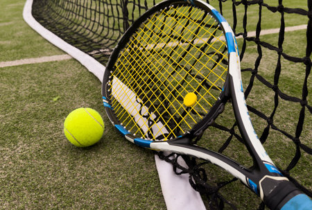 A tennis racket and new tennis ball on a tennis courtの写真素材
