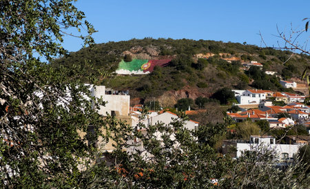 Iconic Portugal flag painted on the mountain hillside is a landmark of the village of Alte in the Algarve regionの写真素材