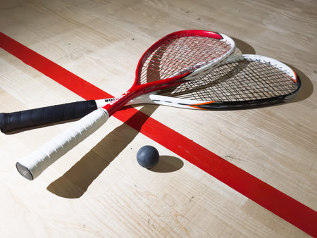 December 5, 2024 Kyiv, Ukraine - Two rackets and two squash balls lie on the parquet floor. Horizontal photoのeditorial素材