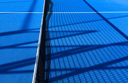 the blue synthetic grass surface of a paddle tennis court, near the netの写真素材