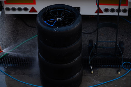 Mechanic performs automotive maintenance on red race car wheel and tire. focused pit stop service...